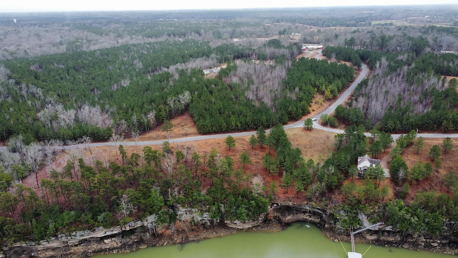 Wide aerial view of The Highland Shores community roads, woods, and lake